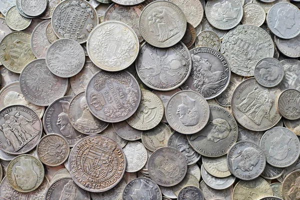 Ancient silver coins in a background photo.