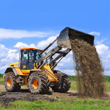 Kalush, Ukrayna 12 Temmuz 2018: Jcb kepçe yükleyici patikadan kasaba Kalush, Ukrayna yakınındaki bir bölümünü onarıyor.