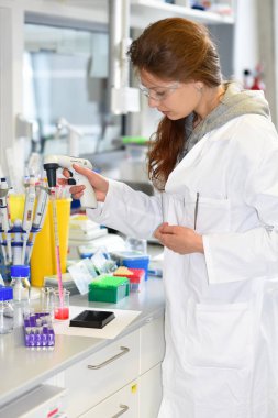 Prag, Çek Cumhuriyeti - 30 Nisan 2017: Araştırmacı bir otomatik pipet biyokimyasal laboratuvar olarak kullanarak kırmızı bir çözüm aktarma gerçekleştirir. Biyokimya ve organik Enstitüsü.