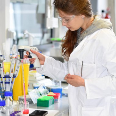 Prag, Çek Cumhuriyeti - 30 Nisan 2017: Araştırmacı bir otomatik pipet biyokimyasal laboratuvar olarak kullanarak kırmızı bir çözüm aktarma gerçekleştirir. Biyokimya ve organik Enstitüsü.