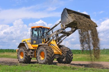 Kalush, Ukrayna 12 Temmuz 2018: Jcb kepçe yükleyici patikadan kasaba Kalush, Ukrayna yakınındaki bir bölümünü onarıyor.