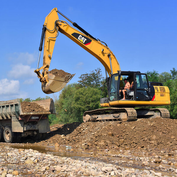 Kalush, Ukraine - August 18, 2018: Loading gravel in the car body on the construction of a protective dam near the town of Kalush.