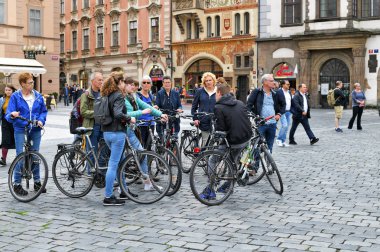 Prag, Çek Cumhuriyeti - 2 Mayıs 2019: Şehir meydanında rehber eşliğinde kiralık bisikletli organize bir turist grubu.