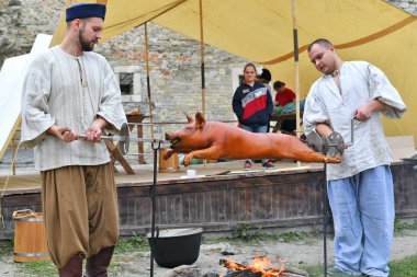 Kamianets-Podilskyi, Ukrayna - 21 Eylül 2019: Tarihi canlandırma Festivali'ne katılanlar, şenlik ateşinde tükürük kavurma olarak da bilinen ızgara domuzu hazırlıyorlar. Eski Kale.