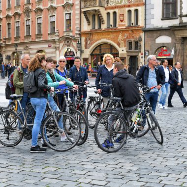 Prag, Çek Cumhuriyeti - 2 Mayıs 2019: Şehir meydanında rehber eşliğinde kiralık bisikletli organize bir turist grubu.