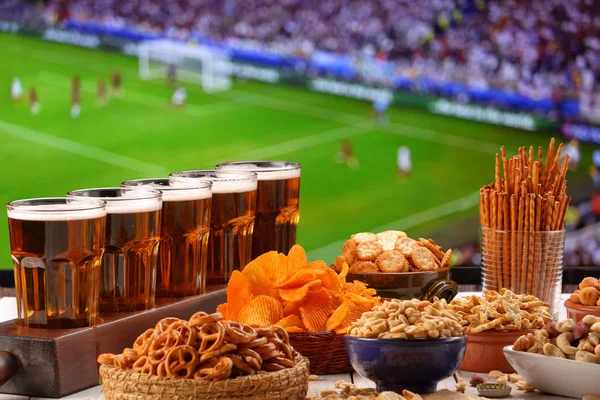 Beer and snack on football match field from tv background