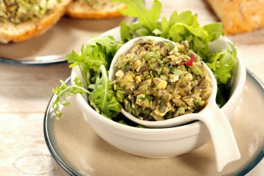 Yumurta ve aragula beyaz bir kase içinde ahşap arka plan üzerinde sağlıklı kahvaltı ile avokado salatası