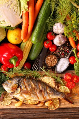 Kavrulmuş patates ve sebze plaka üzerinde ızgara dorada balıkla vintage görünümü kapatın