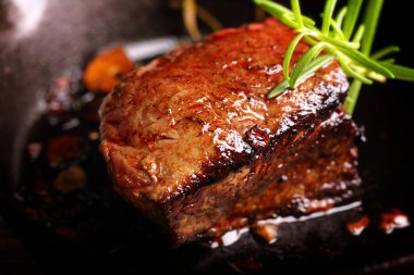 Dökme demir tava tava üzerinde sulu biftek biftek ve otlar baharat 