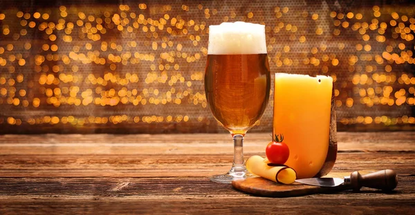 Aperitivo de queijo amarelo com cerveja em fundo vintage de madeira — Fotografia de Stock