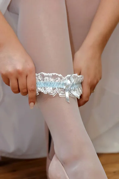 Bride puts on a blue garter — Stock Photo, Image