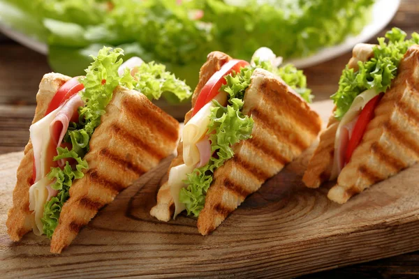 Φρέσκο τοστ σάντουιτς με τυρί, ζαμπόν και ντομάτα σε ξύλινη βάση — Φωτογραφία Αρχείου