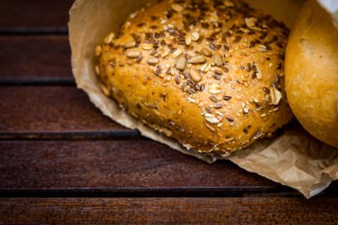 Kağıt, ahşap arka plan üzerinde sarılı taze pişmiş ekmek.