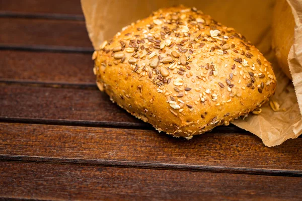 Kağıt, ahşap arka plan üzerinde sarılı taze pişmiş ekmek.