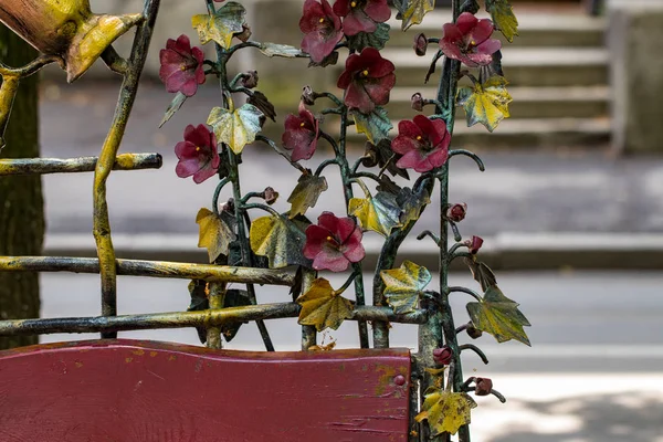 Details, structure and ornaments of forged iron gate. Decorative ornamen with flowers made from metal.