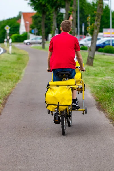 Postman riding his cargo bike carrying out mail in neighborhood.