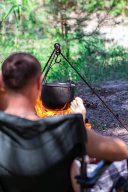 Ateşin üzerinde asılı duran bir turist potası. Kampanyada yemek pişirme.