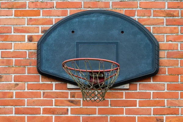 Basketball court outdoor in front of a old brick wall.