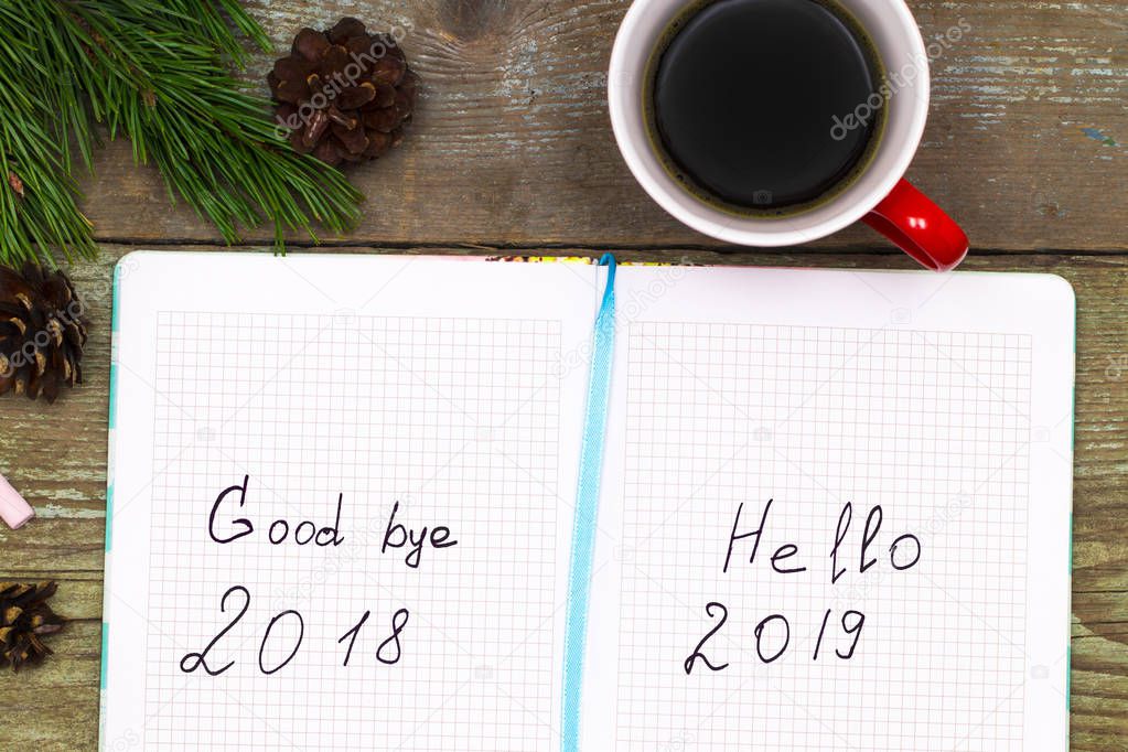  cup of coffee christmas fir tree with cones and notebook with labeled :2019 Hello, goodbye 2018 on wooden  background from above. 