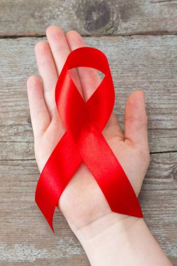 Dünya Yardım Günü ve Ulusal HIV / AIDS ve Yaşlanma Bilinci Ayı konsepti için kadınların el desteğine kırmızı kurdele takıyor.