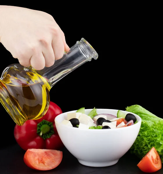 vegetable salad with olive oil pouring from a bottle.