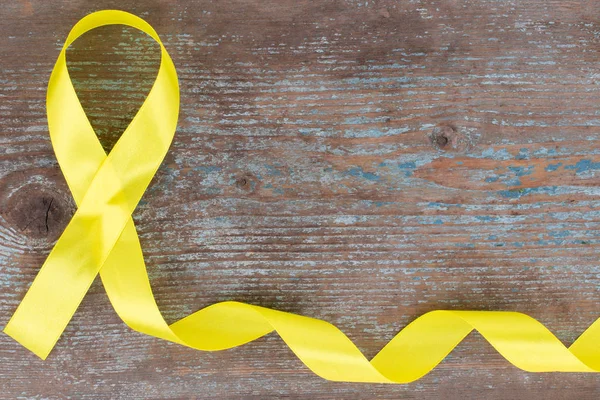 ahşap arka plan kopya alanı ile sarı şerit-çocukluk kanser farkındalık sembolü. 