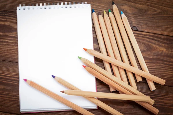 Κενό σημειωματάριο και μολύβι χρώματος στο ξύλινο blackground — Φωτογραφία Αρχείου