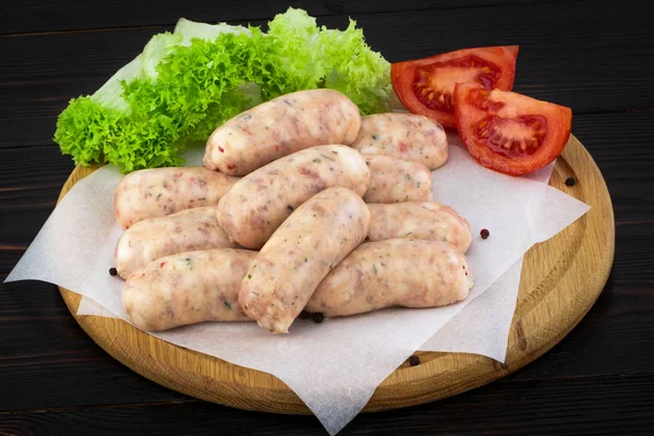 Frische rohe Wurst mit Salat und Tomate auf dem hölzernen Background — Stockfoto