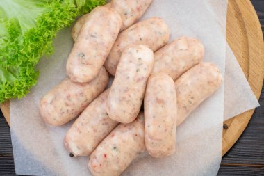 Taze çiğ sosis ahşap arka planda, üstten görünüm