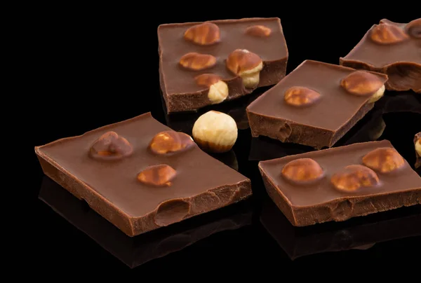 Koyu arka planda fındık ile sütlü çikolata parçaları — Stok fotoğraf
