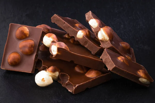 Pezzi di cioccolato al latte con noci su sfondo scuro — Foto Stock