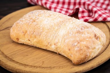 Koyu ahşap sekmesinde bir kesme tahtasında ciabatta ekmek Loaf