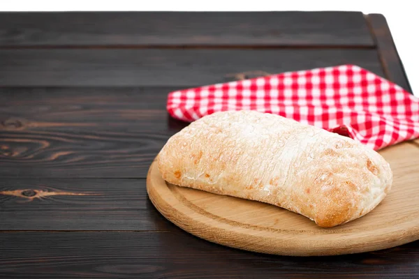 Pão de ciabatta em uma tábua de corte na aba de madeira escura — Fotografia de Stock