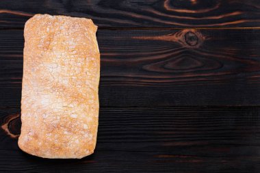  ciabatta bread on a cutting board on the dark wooden table, top