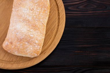  ciabatta bread on a cutting board on the dark wooden table, top