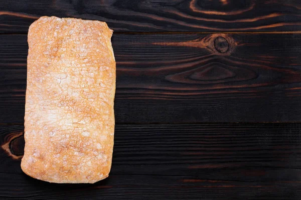 Pão ciabatta em uma tábua de corte na mesa de madeira escura, topo — Fotografia de Stock
