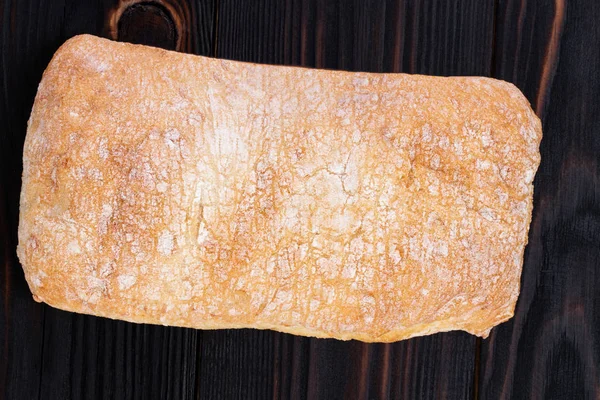 Pane ciabatta su un tagliere sul tavolo di legno scuro, top — Foto Stock