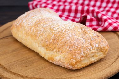 Koyu ahşap sekmesinde bir kesme tahtasında ciabatta ekmek Loaf