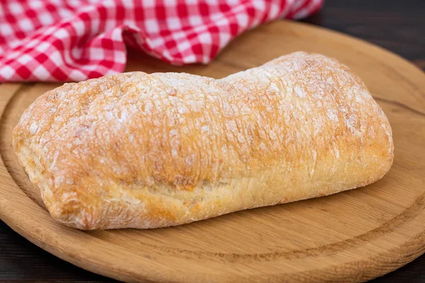 Pão de ciabatta em uma tábua de corte na aba de madeira escura — Fotografia de Stock