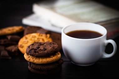 Çikolatalı kurabiye fincan kahve ve ahşap masa üzerinde kitap. Homema