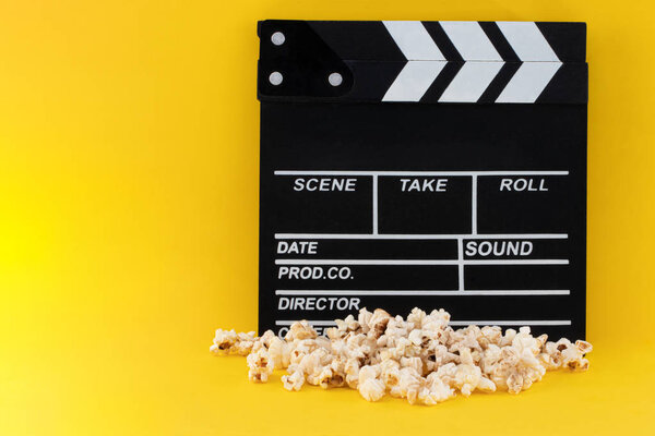 Popcorn and clapperboard on colorful background