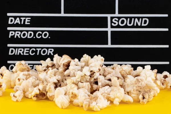 Popcorn a clapperboard na barevném pozadí — Stock fotografie