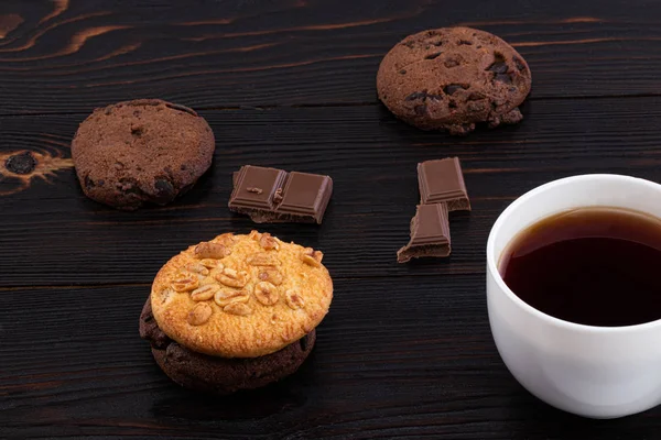Ciasteczka i filiżanka kawy na ciemnym drewnianym tle — Zdjęcie stockowe