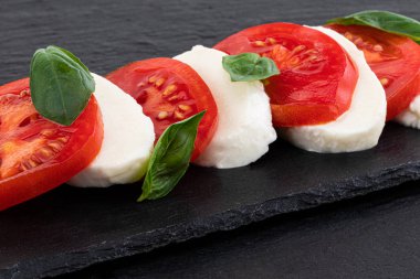 Caprese salatası. Taş masa üzerinde mozzarella peyniri, domates ve fesleğen bitki yaprakları