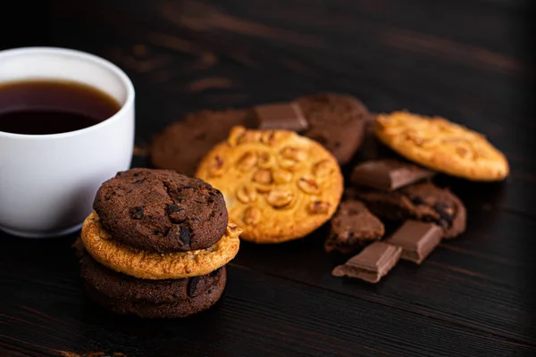 Cookies and cup of coffee on dark wooden background — Stock Photo, Image