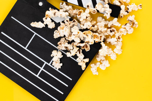 Popcorn and clapperboard on colorful background. Top view.
