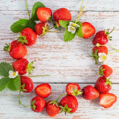 Çilekli çelenk. Çiçekli taze çilekler ve ahşap arka planda fotokopi alanı olan yapraklar. Üst görünüm. 
