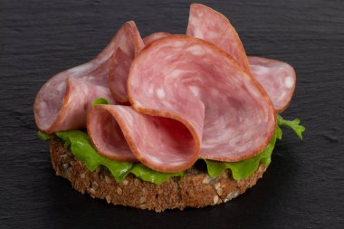 Arkaplanda salamlı ve marullu sandviç..