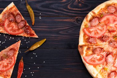Sosisli pizza ve koyu arkaplanda kırmızı biber, fotokopi alanı olan üst manzara..