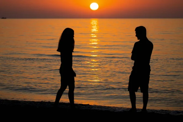 日没時に海岸にいた男と女のシルエットを愛し — ストック写真
